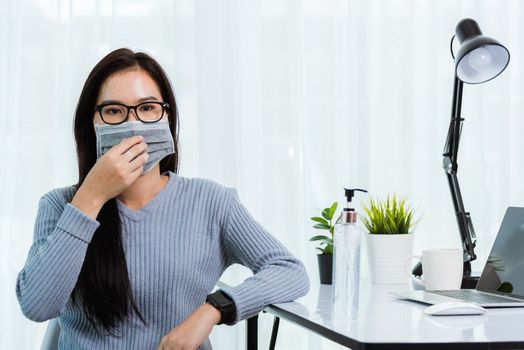 Asian young business beautiful woman during wearing face mask protective working from home office with laptop computer desk he quarantines disease coronavirus or COVID-19 virus