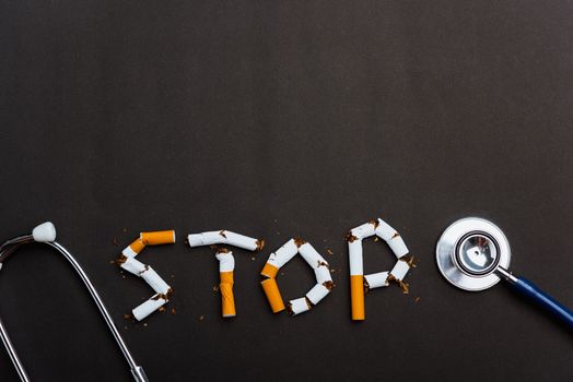 31 May of World No Tobacco Day, no smoking close up word STOP spelled text of the pile cigarette or tobacco and doctor stethoscope on black background with copy space, and Warning lung health concept