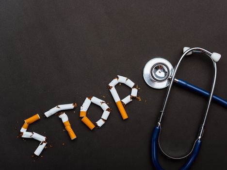 31 May of World No Tobacco Day, no smoking close up word STOP spelled text of the pile cigarette or tobacco and doctor stethoscope on black background with copy space, and Warning lung health concept