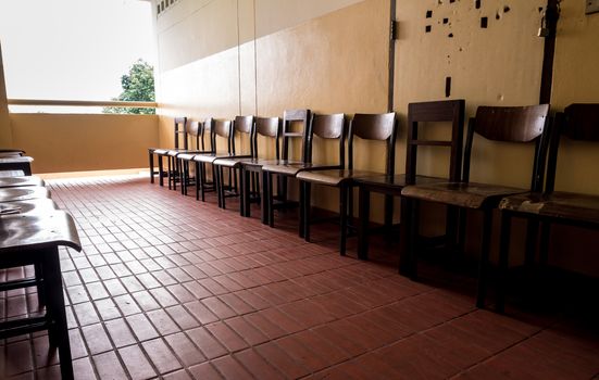 Unused student chair store in front of the broken door of an old classroom