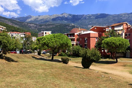 Colorful urban valley of the city of Budva in Montenegro against the background of a mountain range and a blue sky with white clouds.