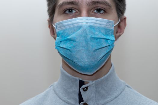 Young man in a medical mask smiles, portrait, close up, health care concept