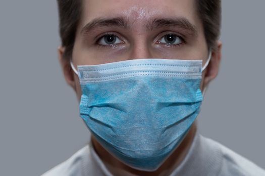 Young man in a medical mask smiles, portrait, close up, health care concept