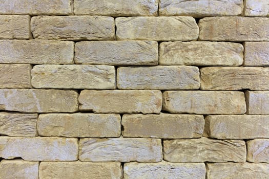 Texture and background of the wall of the old stone from beige-golden sandstone in the form of a brickwork.