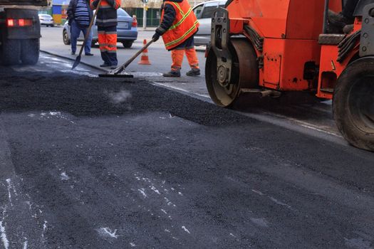 The texture and background of the new freshly laid asphalt against the background of the construction team road service and construction equipment.