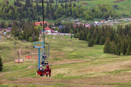 Mountain lift lowers tourists into the valley to the village and the foot of the mountain on the background of the summer mountain landscape in the Carpathians