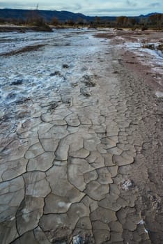 Cracked red clay and white salt on the surface in a dried riverbed in the desert of New Mexico, USA