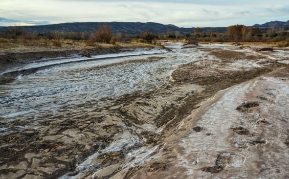 Cracked red clay and white salt on the surface in a dried riverbed in the desert of New Mexico, USA