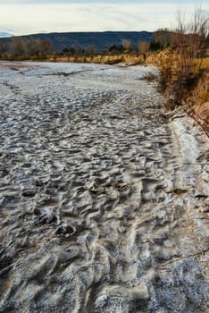 Cracked red clay and white salt on the surface in a dried riverbed in the desert of New Mexico, USA