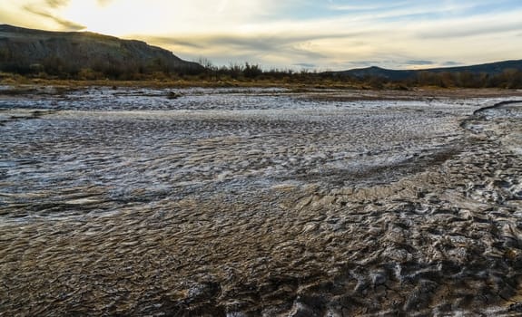 Cracked red clay and white salt on the surface in a dried riverbed in the desert of New Mexico, USA