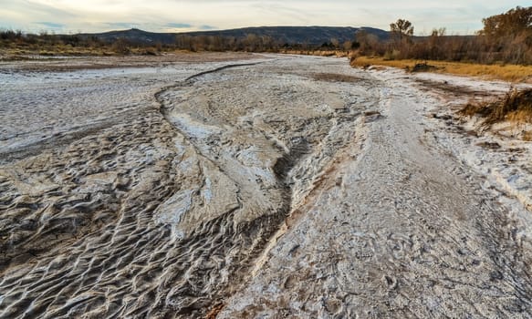 Cracked red clay and white salt on the surface in a dried riverbed in the desert of New Mexico, USA