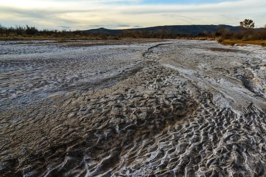 Cracked red clay and white salt on the surface in a dried riverbed in the desert of New Mexico, USA