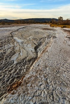 Cracked red clay and white salt on the surface in a dried riverbed in the desert of New Mexico, USA