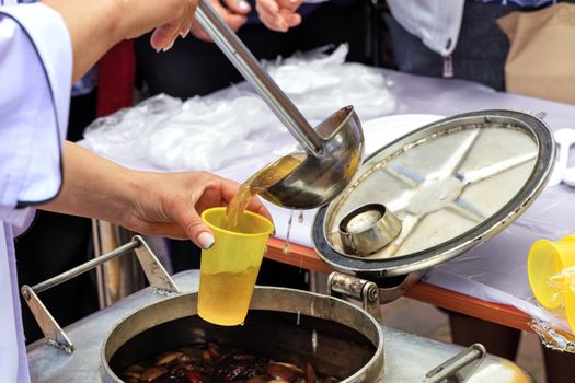 The concept of caring for the poor and the elderly: social workers feed people with fruit compote on the street.