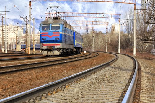 The prospect of many multi-lane railways for electric trains with overhead power lines in the early spring morning, high-rise buildings in the background.