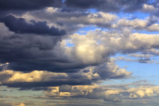 Storm clouds float across the sky illuminated by the rays of the setting sun.