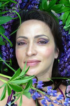 A beautiful woman is relaxing in nature among blooming purple lupines on a Sunny summer day