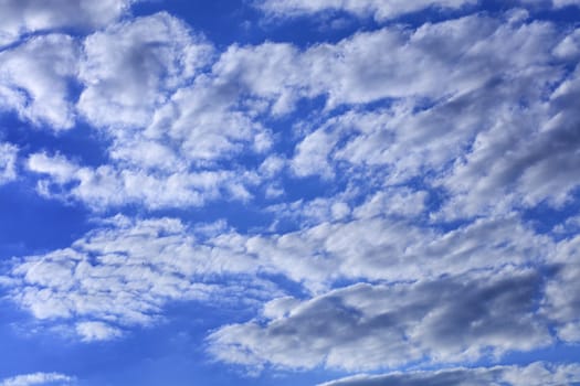 Blue sky with white and gray condensing fluffy clouds.