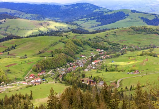 Mountain landscape with a view of the village from a height of a mountain lift in spring from a mountain peak, nature in the Carpathians.