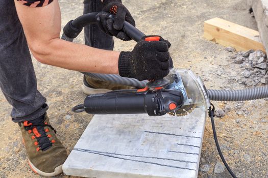 The worker uses a diamond cutting disc and an angle grinder to cut the paving bar and metal plate.