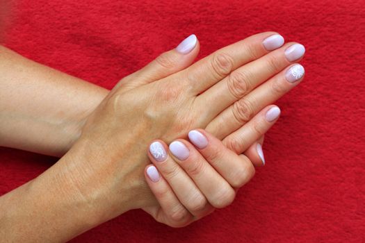 Beautiful female nails with beautiful French manicure Ombre peach and white on a red background.