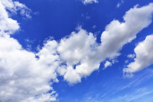 In the blue sky white fluffy clouds strive skyward, dividing the picture diagonally.