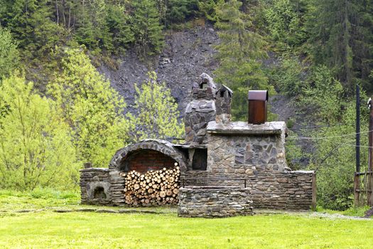 Old stone oven with wood, spit for meat and a smokehouse for cooking on the street in the Carpathians.