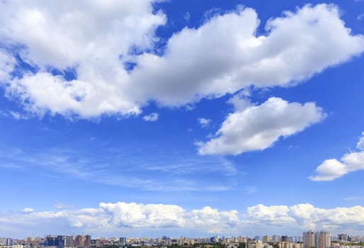 High blue sky with large white clouds floating above the urban landscape.