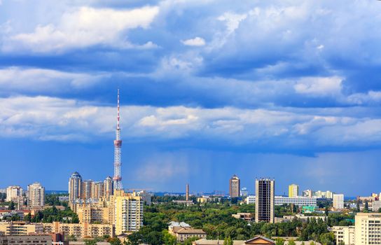 Cityscape of the summer city of Kyiv with a television tower and residential quarters in the impending thunderclouds on the horizon.