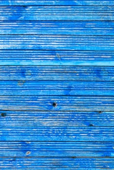 Parallel wooden old planks are painted with blue weathered and peeling paint classic light blue color, vertical image with texture of old wood.