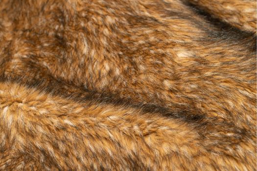Close-up of a fluffy dark brown faux fur fabric with a background texture. Brown artificial fabric, can be used as a background. Fur for toys or clothing. Eco-friendly replacement of natural fur.