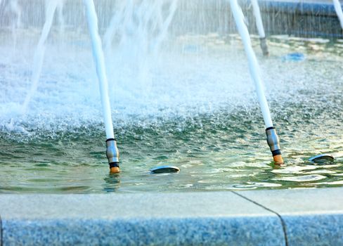 The city fountain is made of polished granite, powerful jets of water are supplied from metal nozzles, creating a beautiful water carousel.