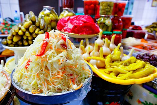 Lettuce made from sauerkraut, carrots and sweet peppers against other fermented and pickled vegetables in a blur is an excellent recipe for healthy and tasty food, close-up.