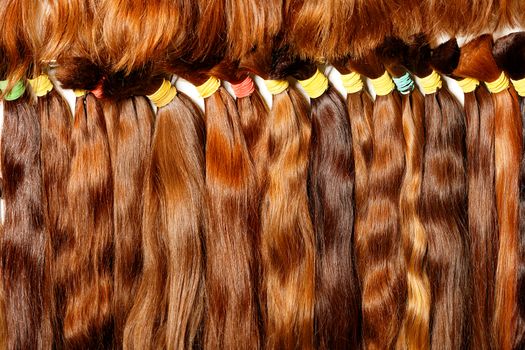 Natural brown with a different shade, shiny, colored shiny healthy human hair bundles for extension and weave wigs making. Haircare female hair, technology, style and beauty concept.