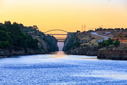 Wide entrance and view of transport bridges in the Corinth Canal in Greece in the rays of the rising sun and the horizon in the morning haze of the sea, image with copy space.