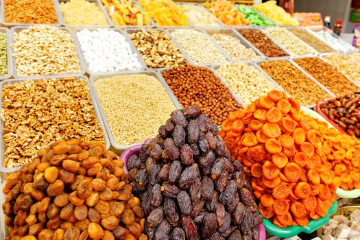Slides with dates, dried apricots, almonds, hazelnuts, walnuts, cashews in blur are sold on the shelves of the eastern market.