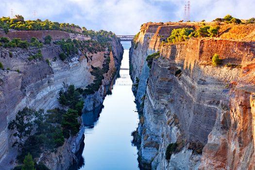 A new summer day begins above the Corinth Canal, the morning bright rising sun of Greece ignites the open granite shores, a view of the Gulf of Corinth from above.