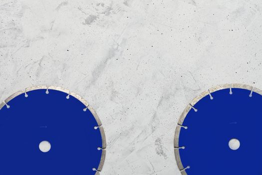 Blue cutting blades with diamond for cutting concrete and reinforced concrete using an angle grinder on a gray concrete background, image with copy space.