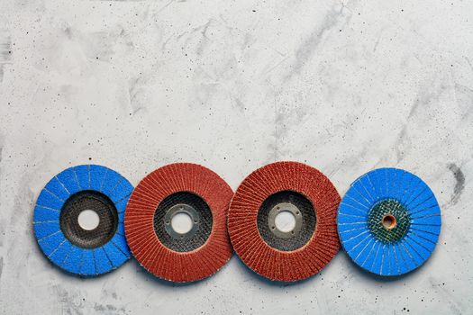 Set of grinding abrasive emery discs for grinding of the metal, wood and stone on the gray concrete background, close-up, image with copy space.