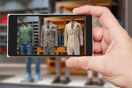 Male mannequin on smartphone screen. Sale of mens clothing. Showcase clothing store.