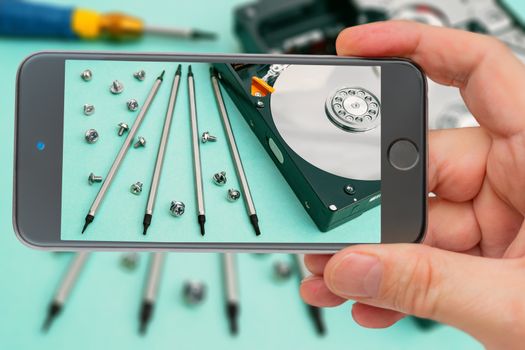 Computer hard drive on smartphone screen. Set of screwdrivers for repair. Computer repair. Computer hard drive.
