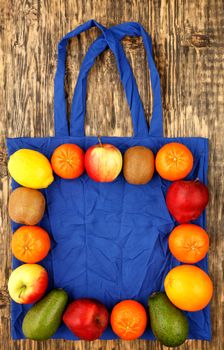 Eco-friendly cotton bag in blue color against a wooden background. Zero waste concept, plastic-free, eco-friendly shopping with fruits, image with copy space.