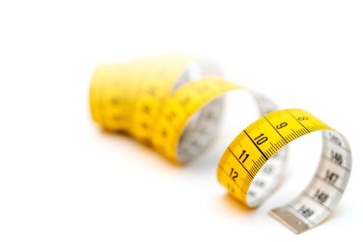 Yellow measuring tape on white background. Measurement of length and circumference. Lose weight and get fat.