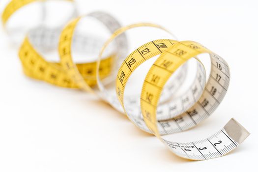 Yellow measuring tape on white background. Measurement of length and circumference. Lose weight and get fat.