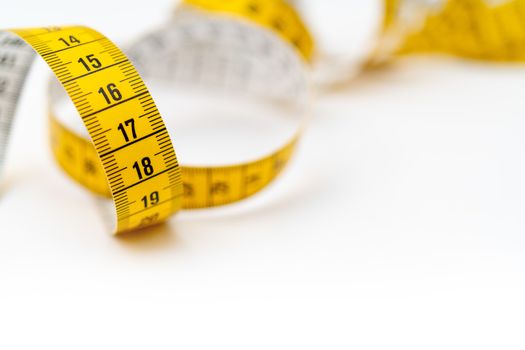 Yellow measuring tape on white background. Measurement of length and circumference. Lose weight and get fat.