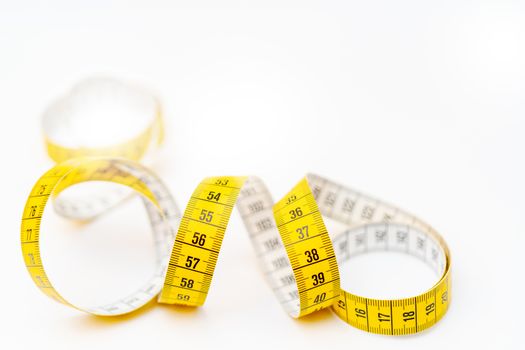 Yellow measuring tape on white background. Measurement of length and circumference. Lose weight and get fat.