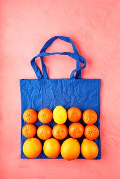 Eco-friendly cotton bag in classic blue color against a peach color background. Zero waste concept, plastic-free, eco-friendly shopping with fruits and vegetables, image with copy space.