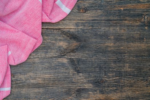 Red and white kitchen towel lies on wooden table. Texture of painted wood. Textured fabric folds.