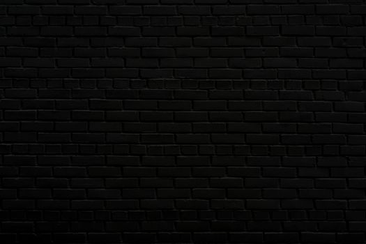 The black wall of the house. Old brick wall. Black paint on a brick wall.