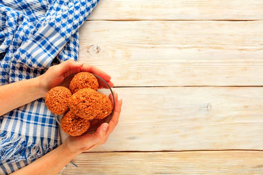 Homemade energy balls with walnuts, peanuts, honey and a banana in a glass bowl, housewife puts on a light wooden table next to a blue napkin. Copy space. Flat lay, top view.
